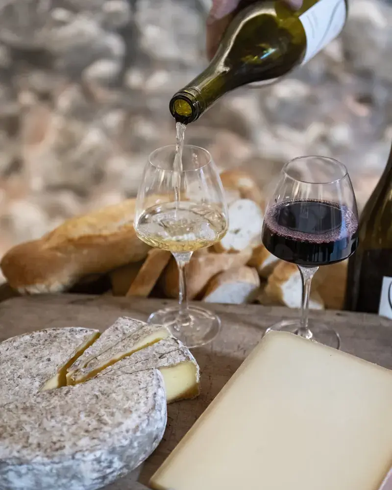 Table dressée dans les vignes avec fromages de Savoie, charcuterie et verres de vin local au coucher du soleil