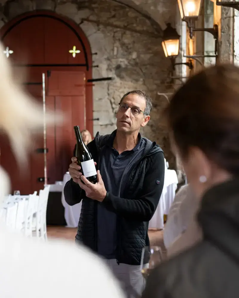 Vigneron savoyard servant un verre de Mondeuse directement depuis le fût dans sa cave familiale